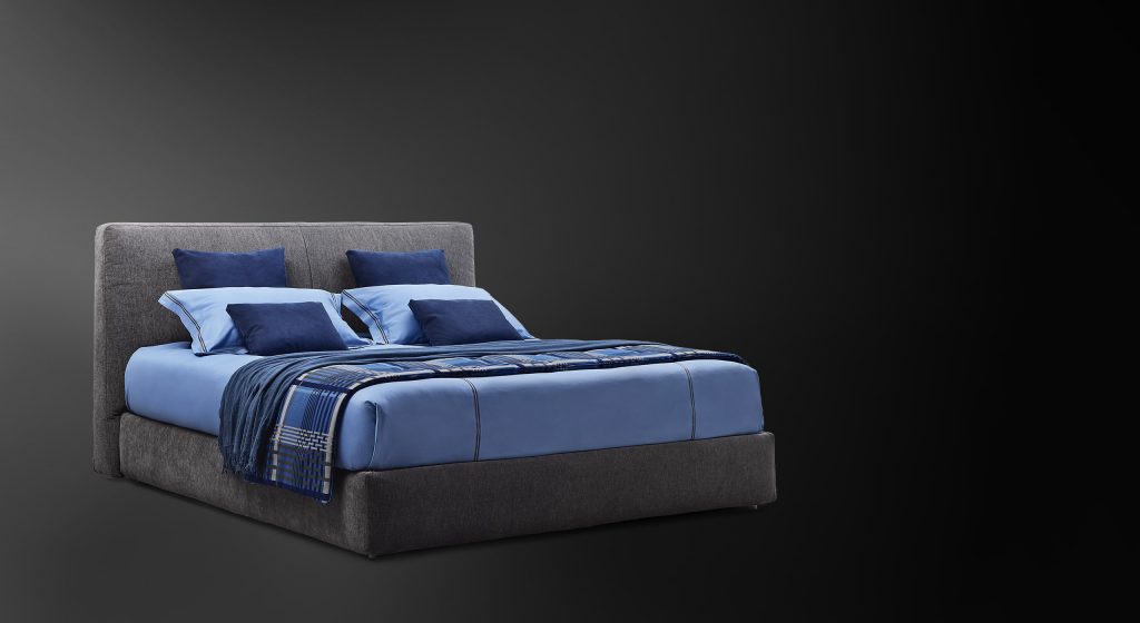 Modern double bed made with a high and thick headboard, richly padded in a dark gray tone