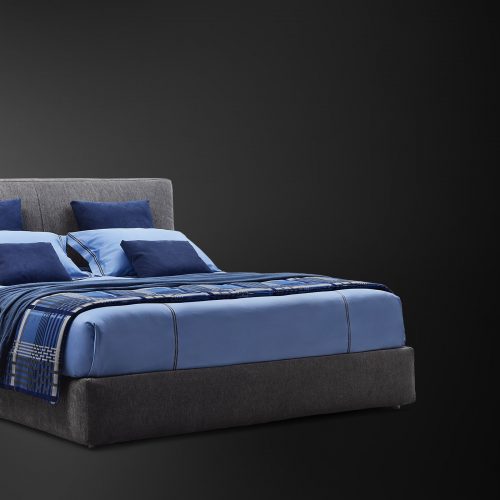 Modern double bed made with a high and thick headboard, richly padded in a dark gray tone