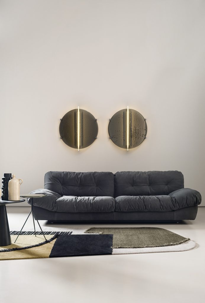 Made of glass and brass, two plate-shaped sconces in bronze tone on a living room