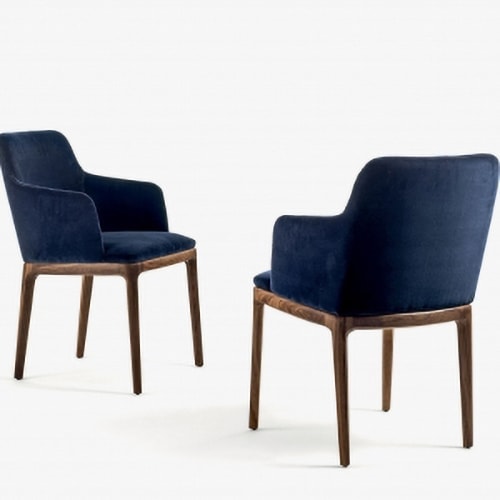 two elegant chairs with armrests made with solid wood legs upholstered in smooth fabric in a dark blue tone on a white background