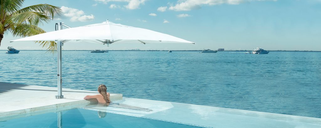 umbrella with low base made of metal and fabric in color and white tone on a pool background