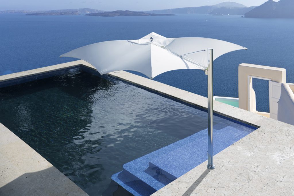 parasol with polished titanium frame on the side and fabric on the top in a white and gray tone on a pool background