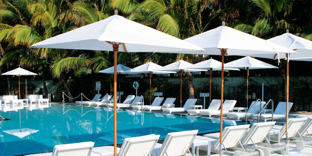 ten umbrellas with a base in the middle made of wood and made of fabric in a tone of white with brown on a pool background