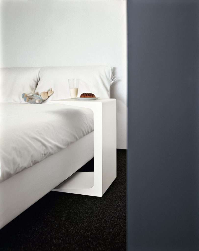 C-shaped side table made of wood throughout its structure in a white tone