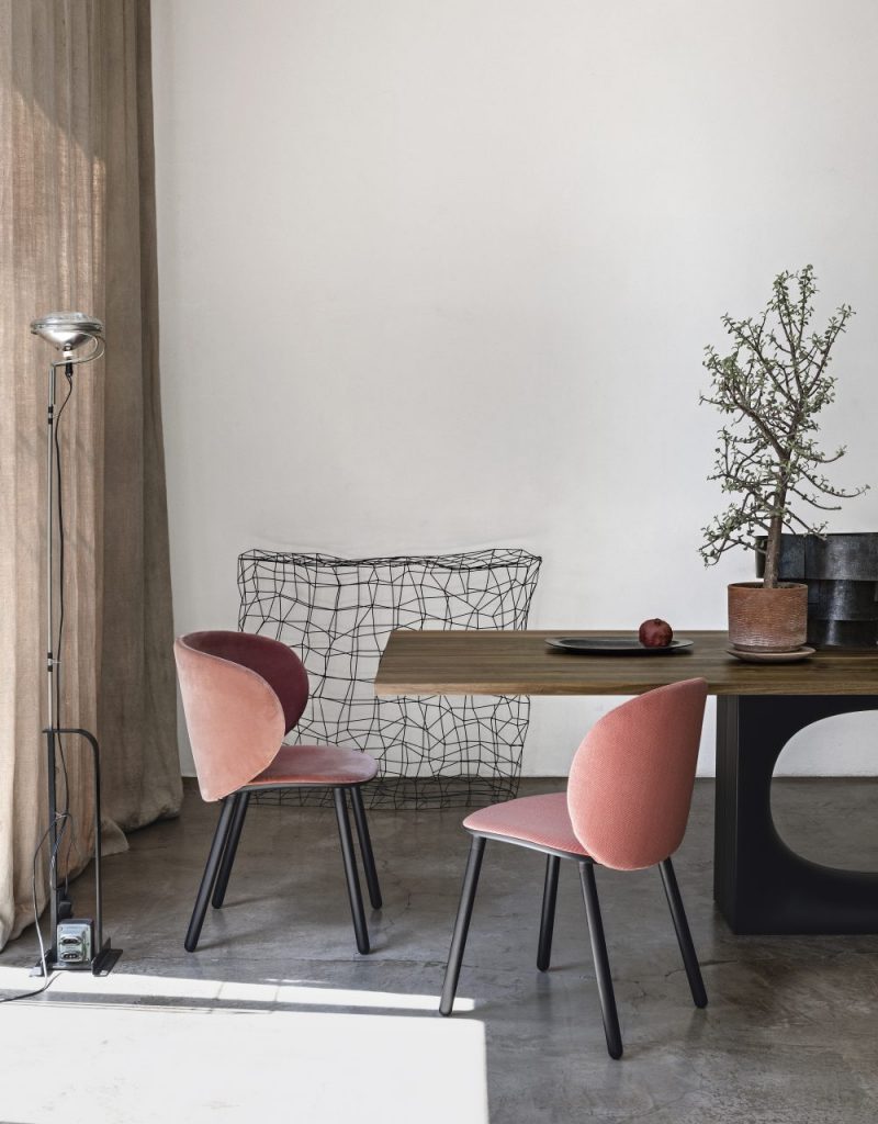 two curved chairs made from wooden legs and fabric in a light pink tone