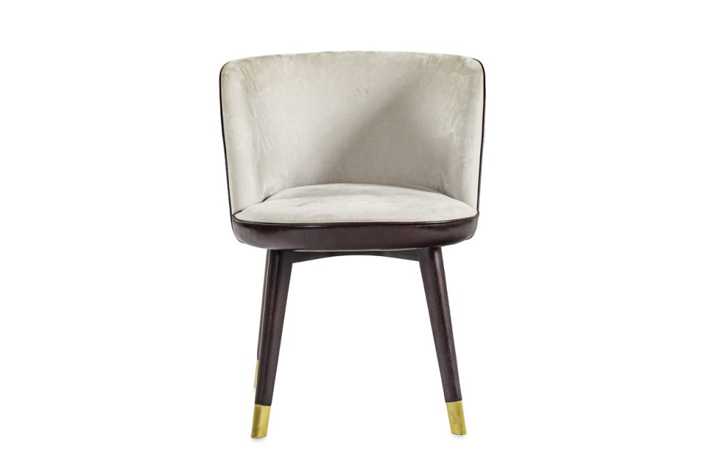 Dining chair made with a base of wooden legs with a brass finish and upholstered in beige leather.