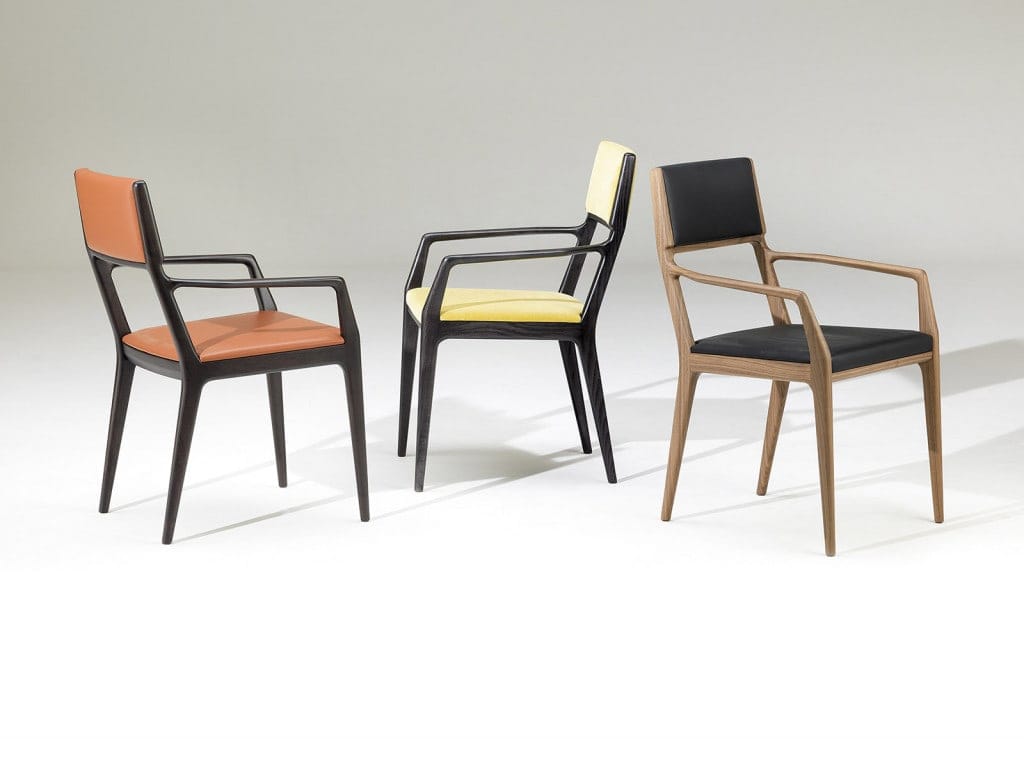 three dining room chairs with armrests made of walnut wood and covered in orange, yellow and black toned fabric