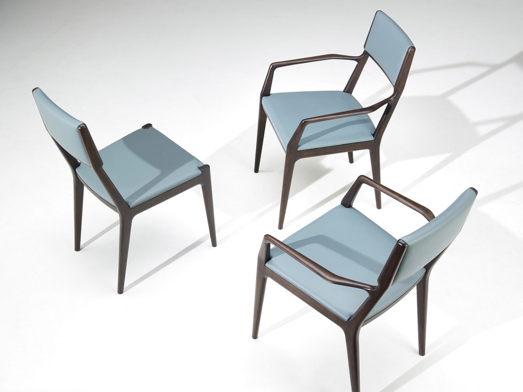 three dining room chairs with armrests made of walnut wood and covered in blue-toned fabric