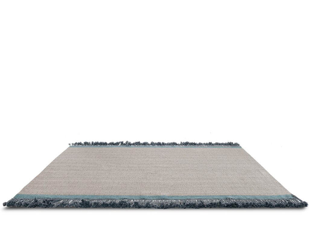 Handmade rug based on fabrics in a gray tone and green finishes on a white background