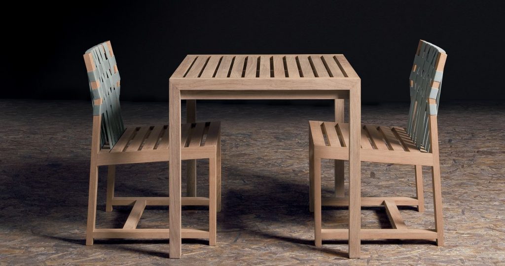 Plaza Sixty Five Table with two chairs on either side with a black wall in the background