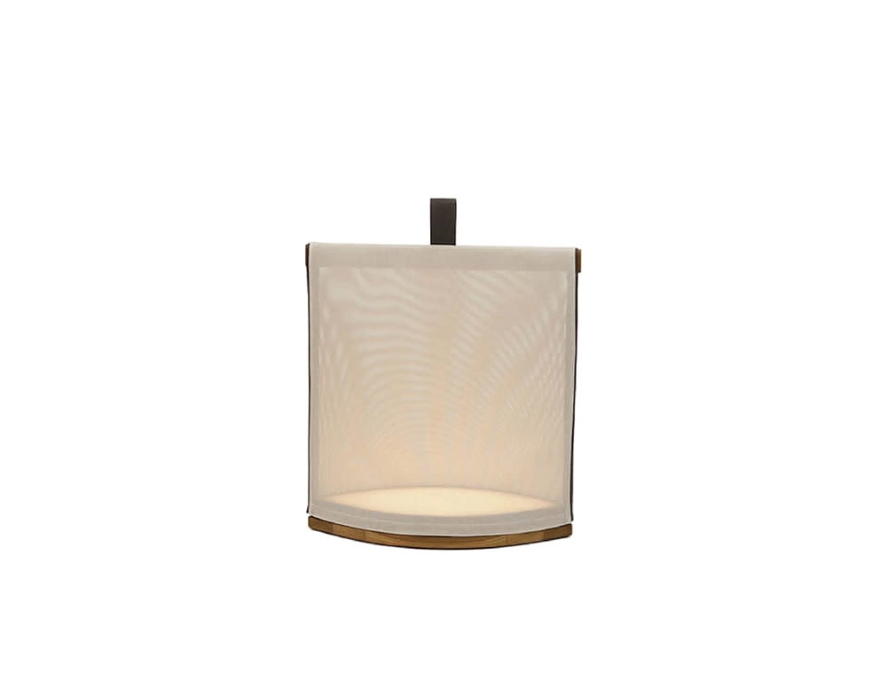 Rod Pillow Lantern radiates a soft ambient glow through its fabric cover and wooden base, creating a warm and inviting outdoor atmosphere.