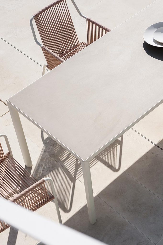 Top view of Plen Air Four Table with a chair next to the table on a patio