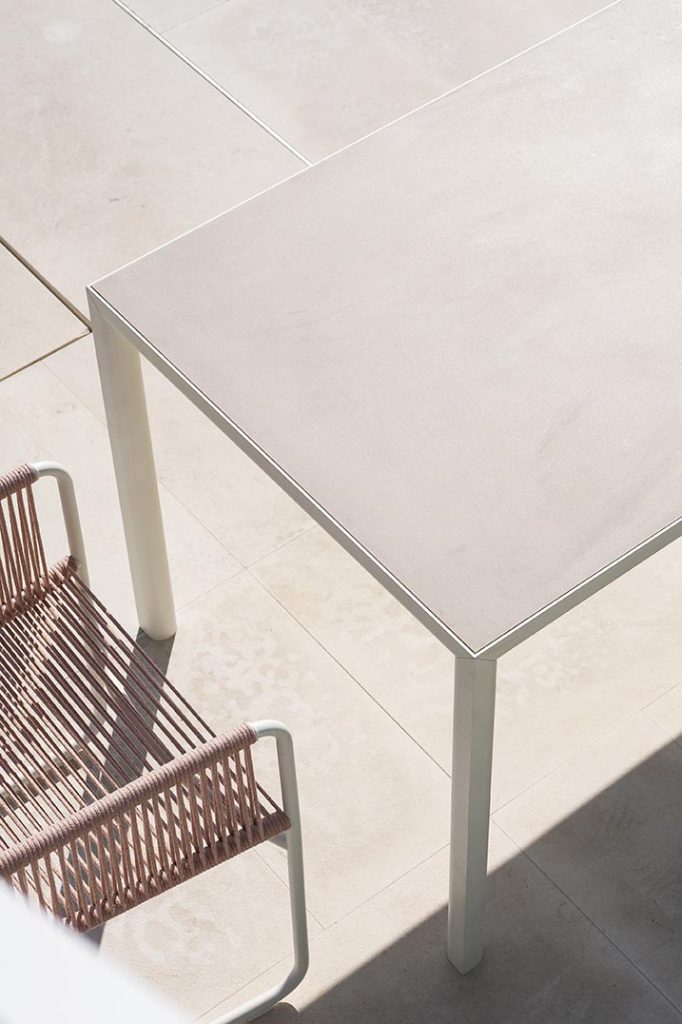 Top view of Plen Air Four Table with a chair next to the table on a patio