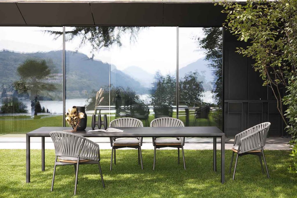 Plen Air Six Table with four chairs surrounding the table in front of a long glass window
