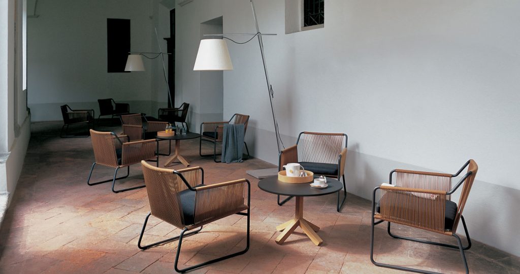 Root Forty Six Side Table in between three armchairs in a circle with a lamp in the background