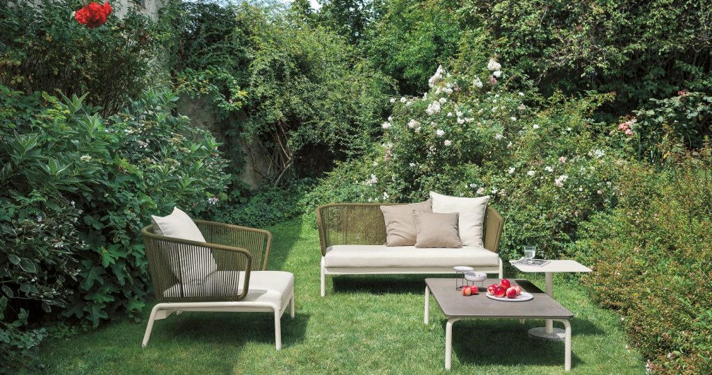Spool Six Coffee Table on grass with a pair of sofas surrounding the tablw