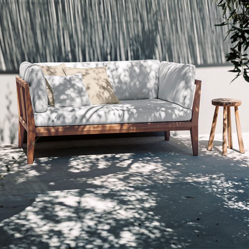 Teka One Sofa in white on a patio with a grey wall in the background and a side table next to the sofa