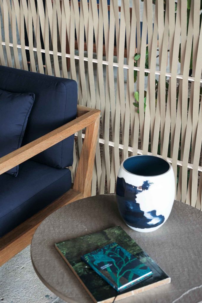 Teka Ten Sofa in blue next to a side table with a book and vase on top