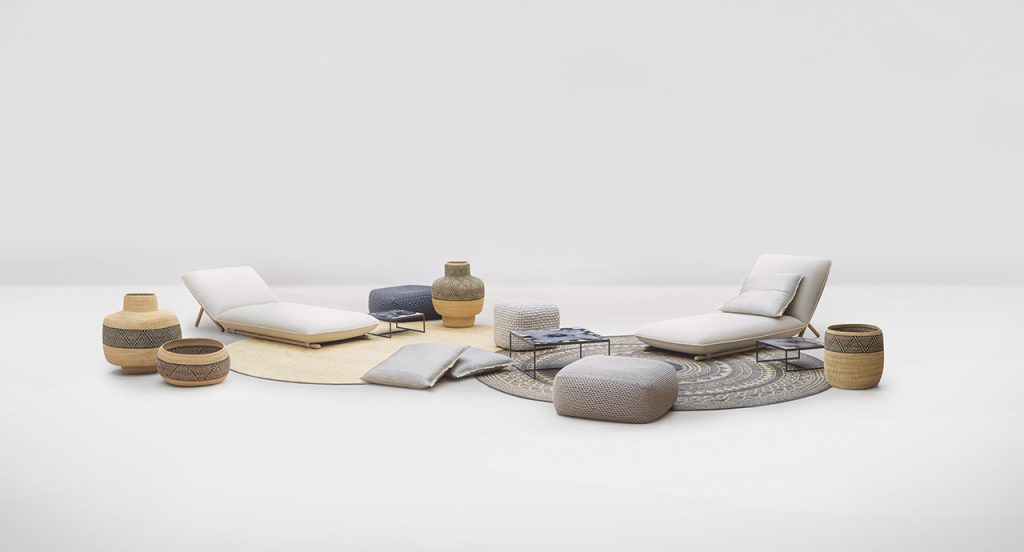 Pair of Hiro Chaise Longue, one on top of a cream colored rug and the other on top of a grey rug in front of a white background