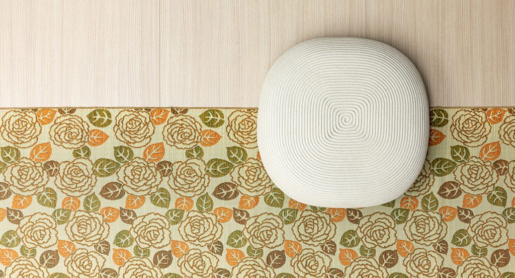 Otto Pouf two thousand twenty one in white on top of a wooden floor and a floral carpet