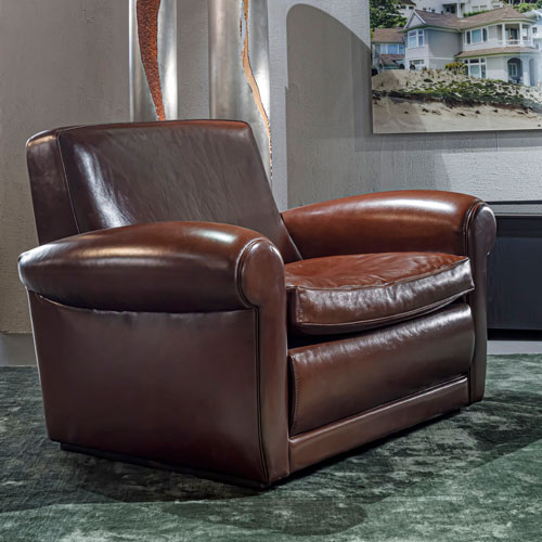 armchair made from beach feet in walnut and upholstered in ceurp in a maroon tone on a white background.
