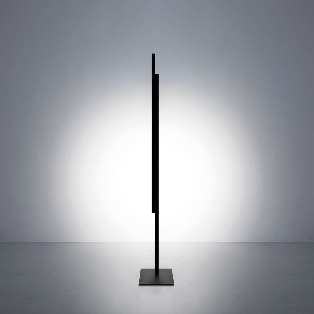Hashi floor lamp in a vertical position shining at a white wall