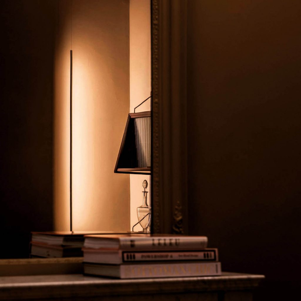 Masai light shining against a tan wall with a tan couch in the foreground