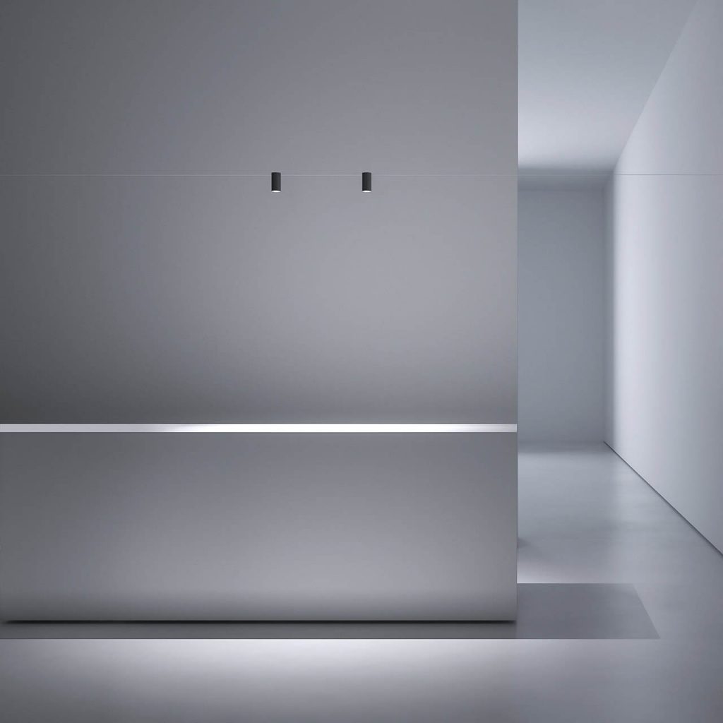 Two Ohm lights shining over a white table in a white walled room