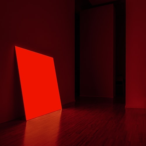 Pablo shining in red in a dark lite room
