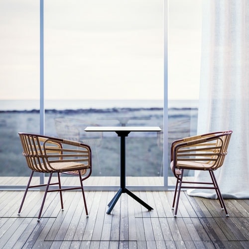 A pair of Raphia Rattan chairs around a table in front of glass windows