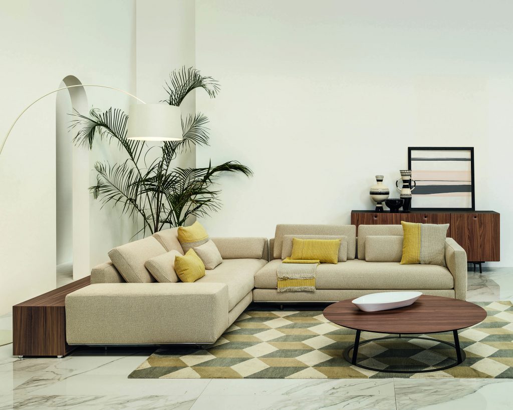Albino Family wide brown top in front of a cream sofa on top of an illusion patterned carpet with a cream wall in the background