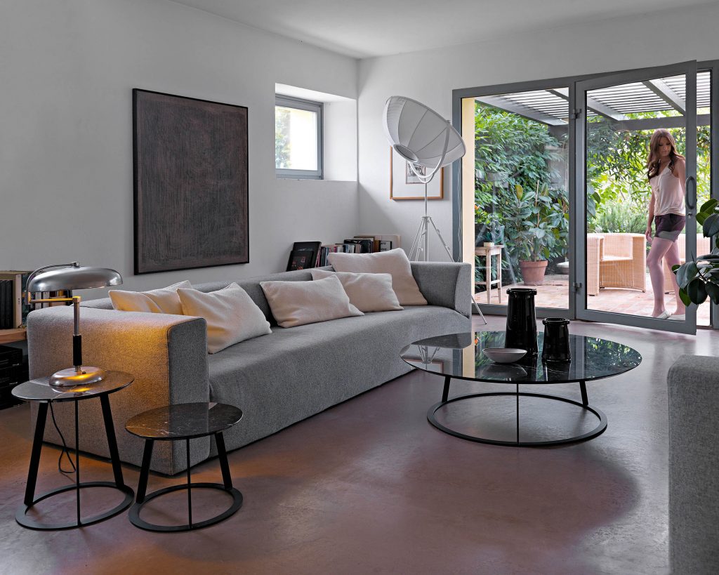 Albino Family wide black top in front of a grey colored sofa on top of a light brown wooden floor