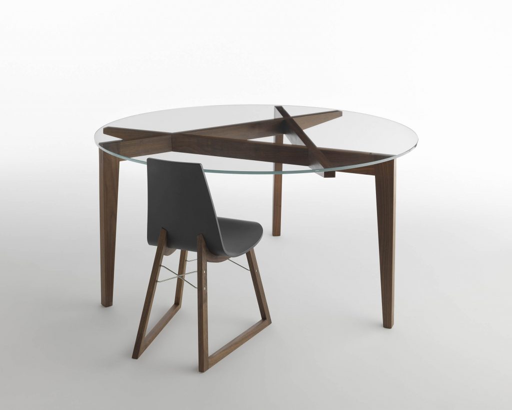 Autoreggente with a circular glass top with a chair in front of it with a grey background