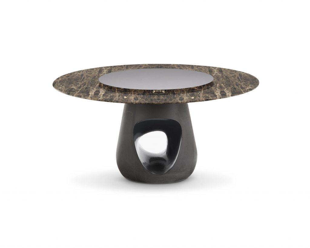 Barbara with a small marble top with a smaller silver circle on top in front of a white background