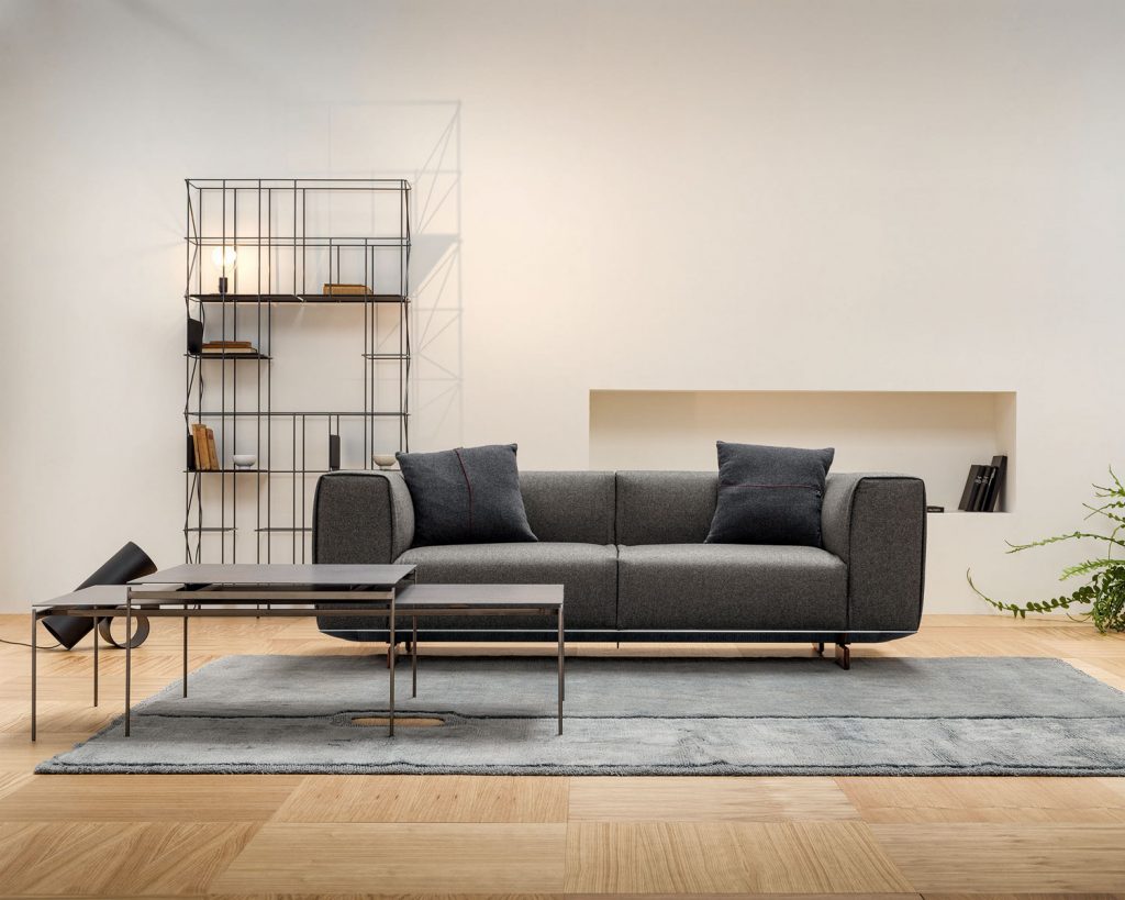 Dark grey colored Coleman on top of a grey rug with wooden floors and white colored walls