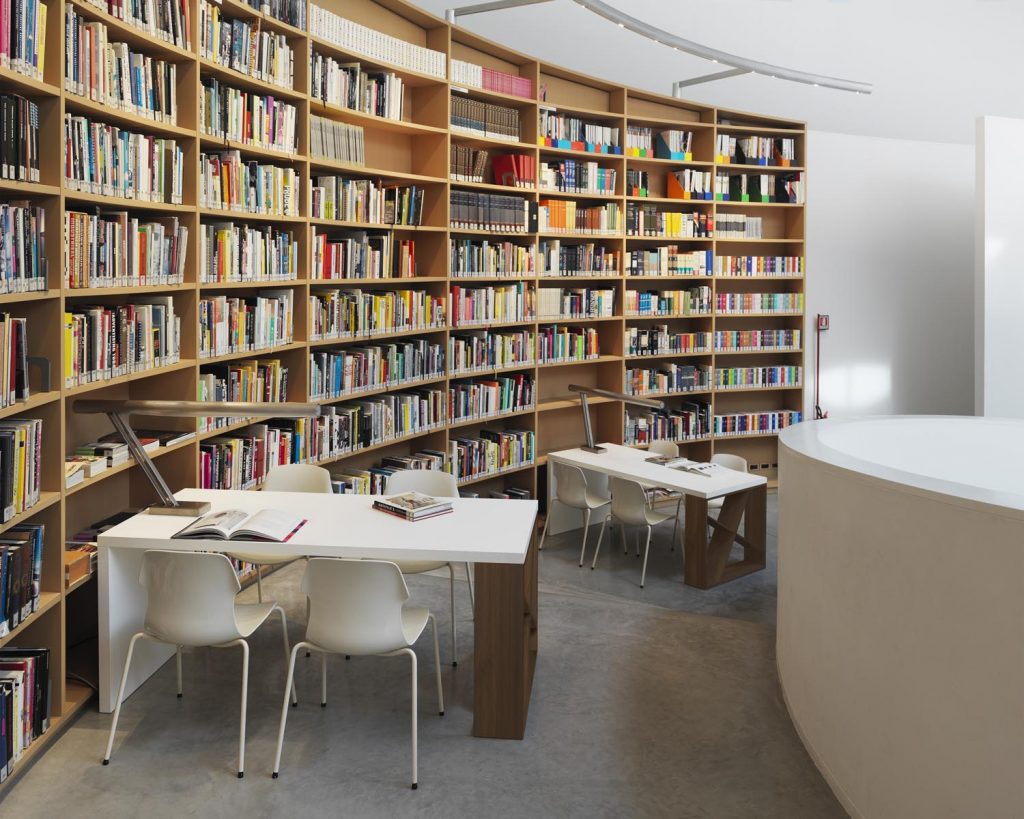 J-Table with a white top in front of a library bookshelf