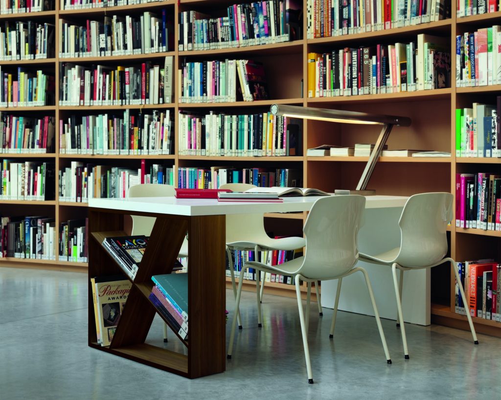 J-Table with a dark wood and white top in front of a library bookshelf