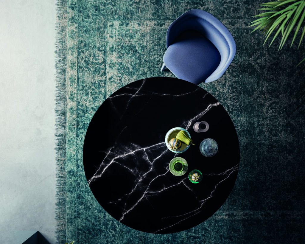 Top angle of Meduse in black marble with a blue chair next to it on a blue rug