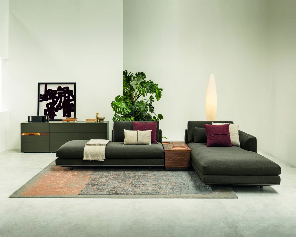 Green colored Miles sofa on top of a multicolored rug and surrounded by white walls