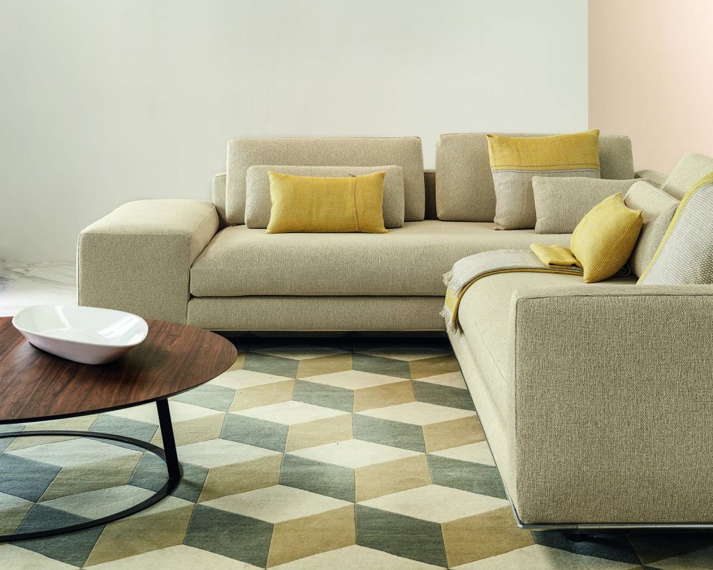 Close up cream colored Miles sofa on a cream colored rug with multicolored patterns