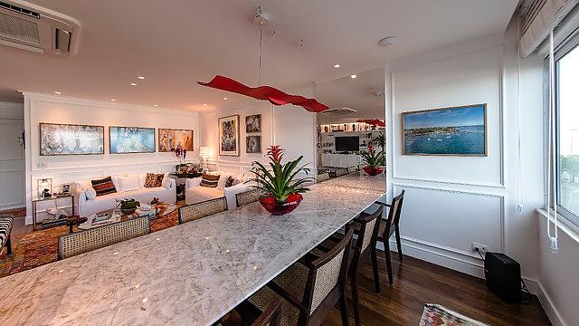 Luce Volante in red hanging over a table with a table in the foreground and paintings hanging on all the walls