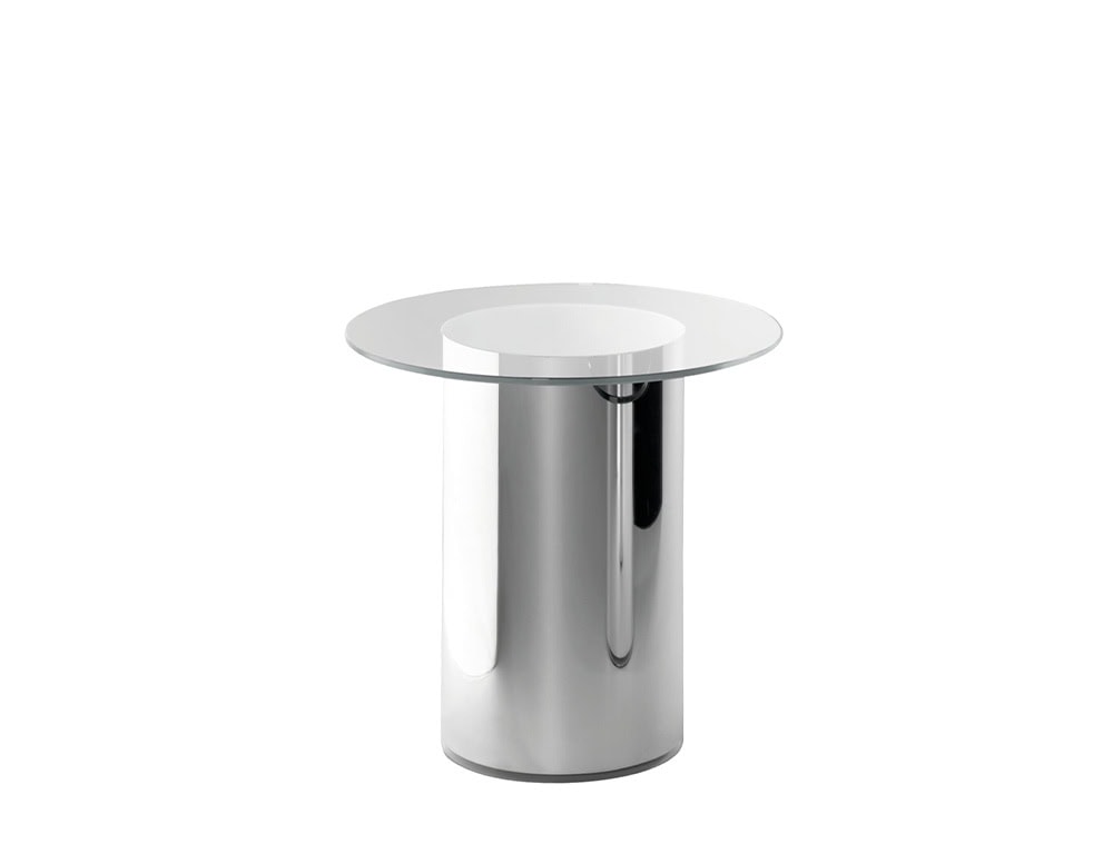 A minimalist side table featuring a cylindrical polished stainless steel base with a round, transparent glass top, combining sleek materials for a contemporary look.