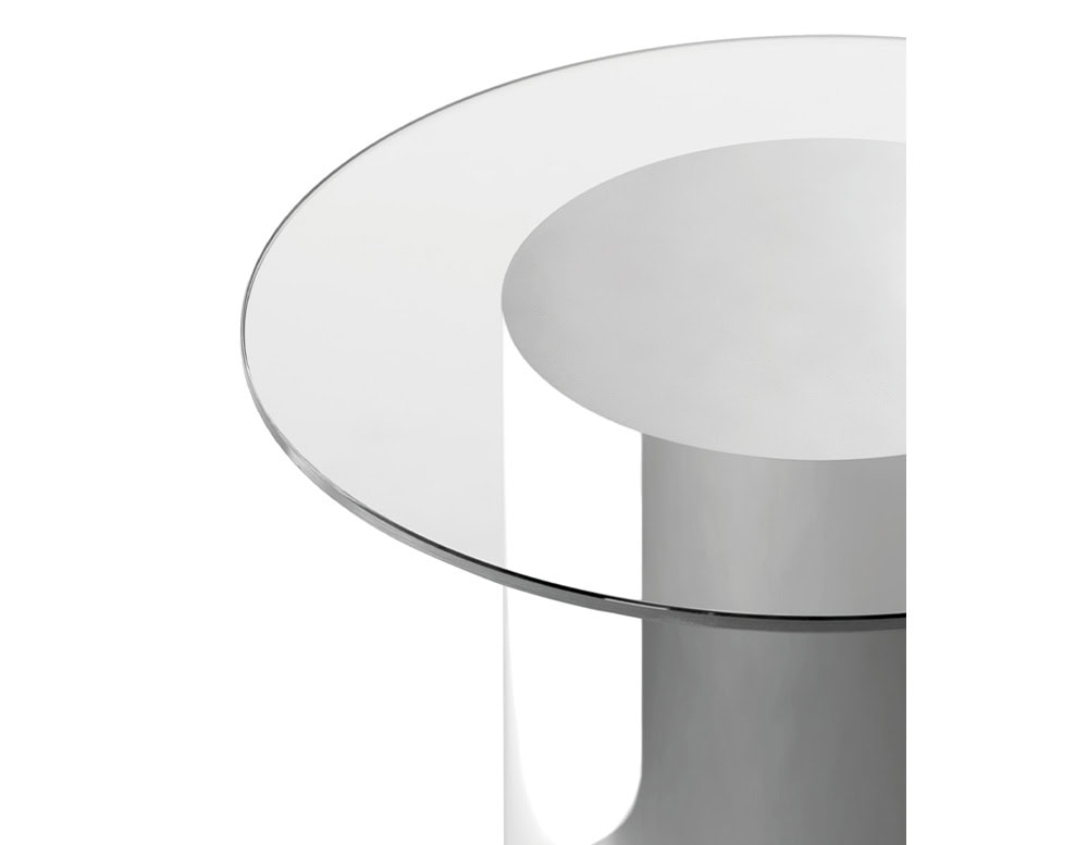 Detail of the table's transparent glass top and polished stainless steel base, highlighting the refined finish and smooth reflective surfaces.