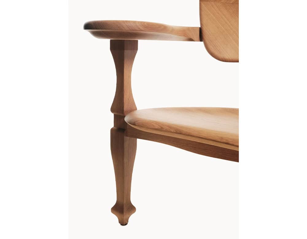 The leg and armrest of the BD Batllo Bench in light oak wood reveal a sculptural silhouette with soft curves and angular accents, highlighting the natural grain and warm tone of the material.