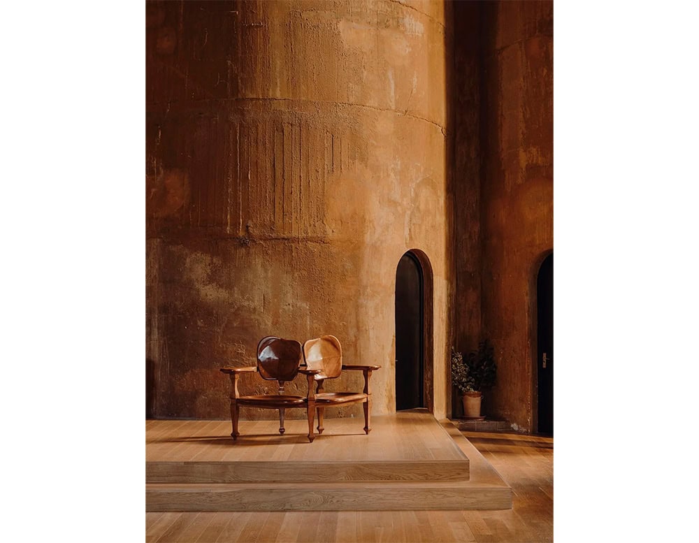 The BD Batllo Bench, crafted in rich brown wood, features twin sculpted backrests and gently curved seats. Its organic form seamlessly integrates into architectural spaces, offering warmth and artisanal elegance.