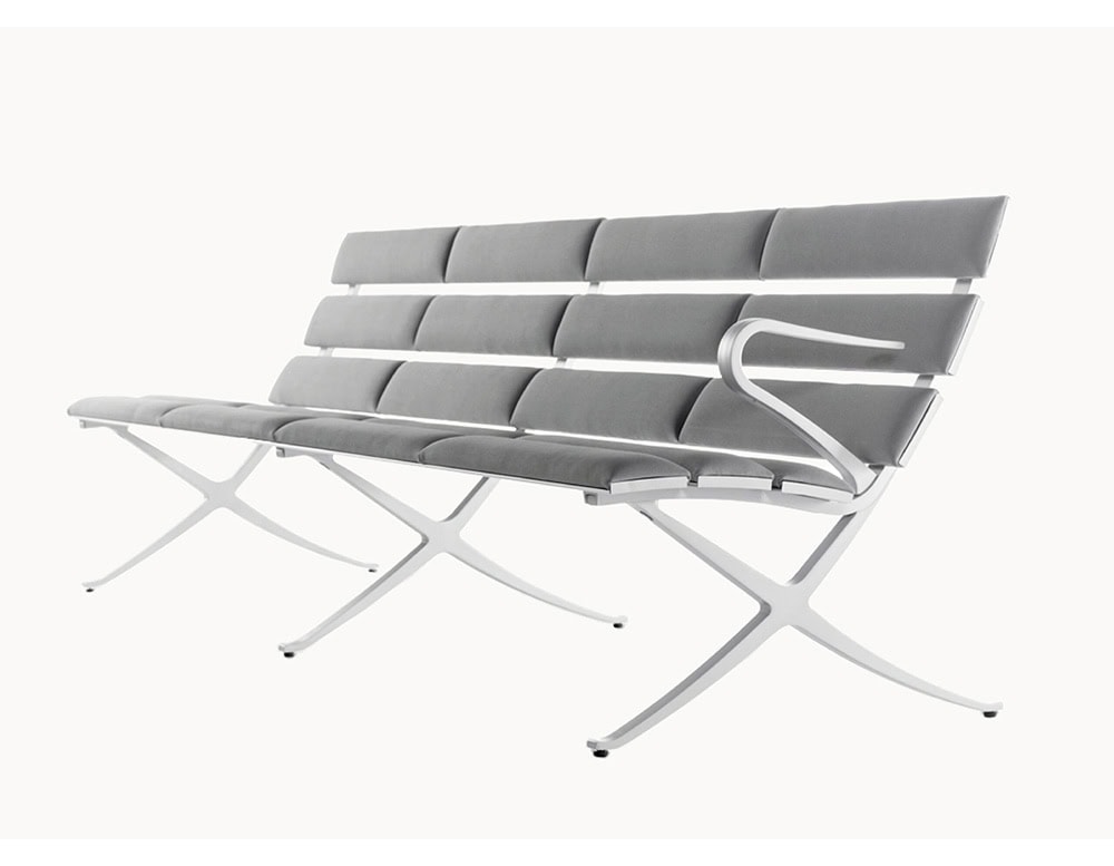 The BD Bench B Outdoor combines sleek aluminum framing with grey cushioned slats, creating a streamlined modular design that is both comfortable and visually light.
