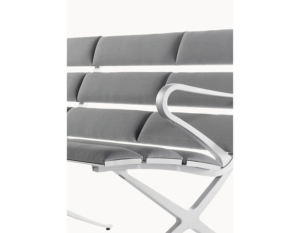 The BD Bench B Outdoor features contoured grey cushions and sleek aluminum framing, offering ergonomic support with a refined, minimalist profile.