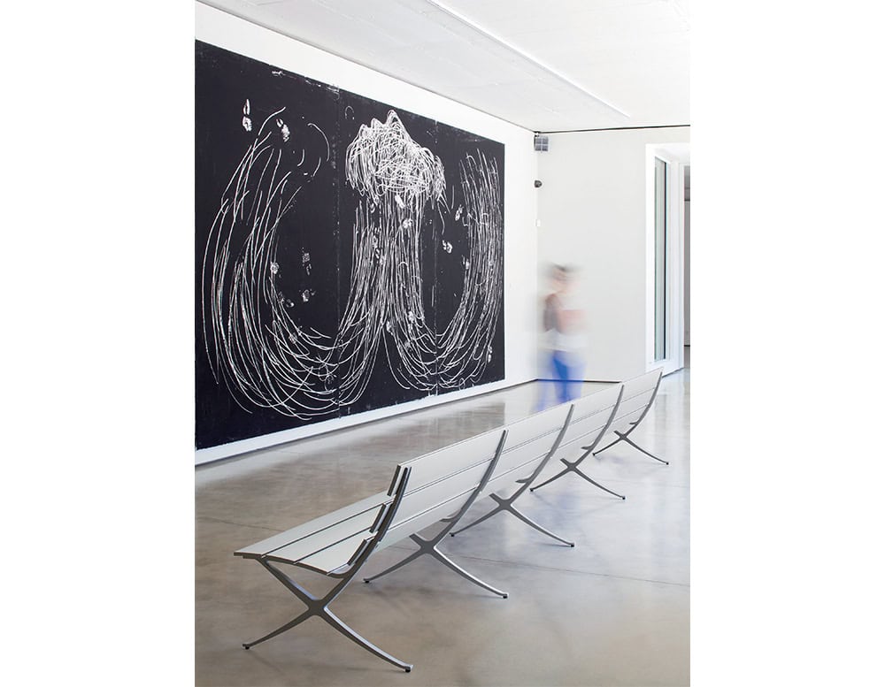 The BD Bench B Outdoor features sleek aluminum slats and angular legs, seamlessly integrating into modern indoor or outdoor spaces while offering minimalist, functional seating.