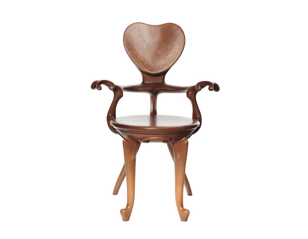 The BD Calvet Armchair emphasizes its sculpted heart-shaped backrest, gracefully curved armrests, and round seat. The warm wood tones display a smooth finish with elegant grain patterns.