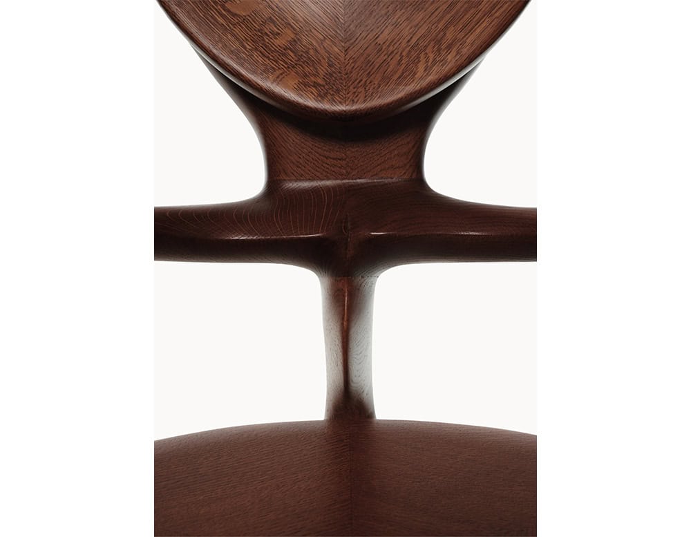 This close-up captures the intersection of the BD Calvet Armchair’s backrest and arms. The sculpted curves in polished oak show warm brown tones with natural wood grain, emphasizing its fluid craftsmanship.